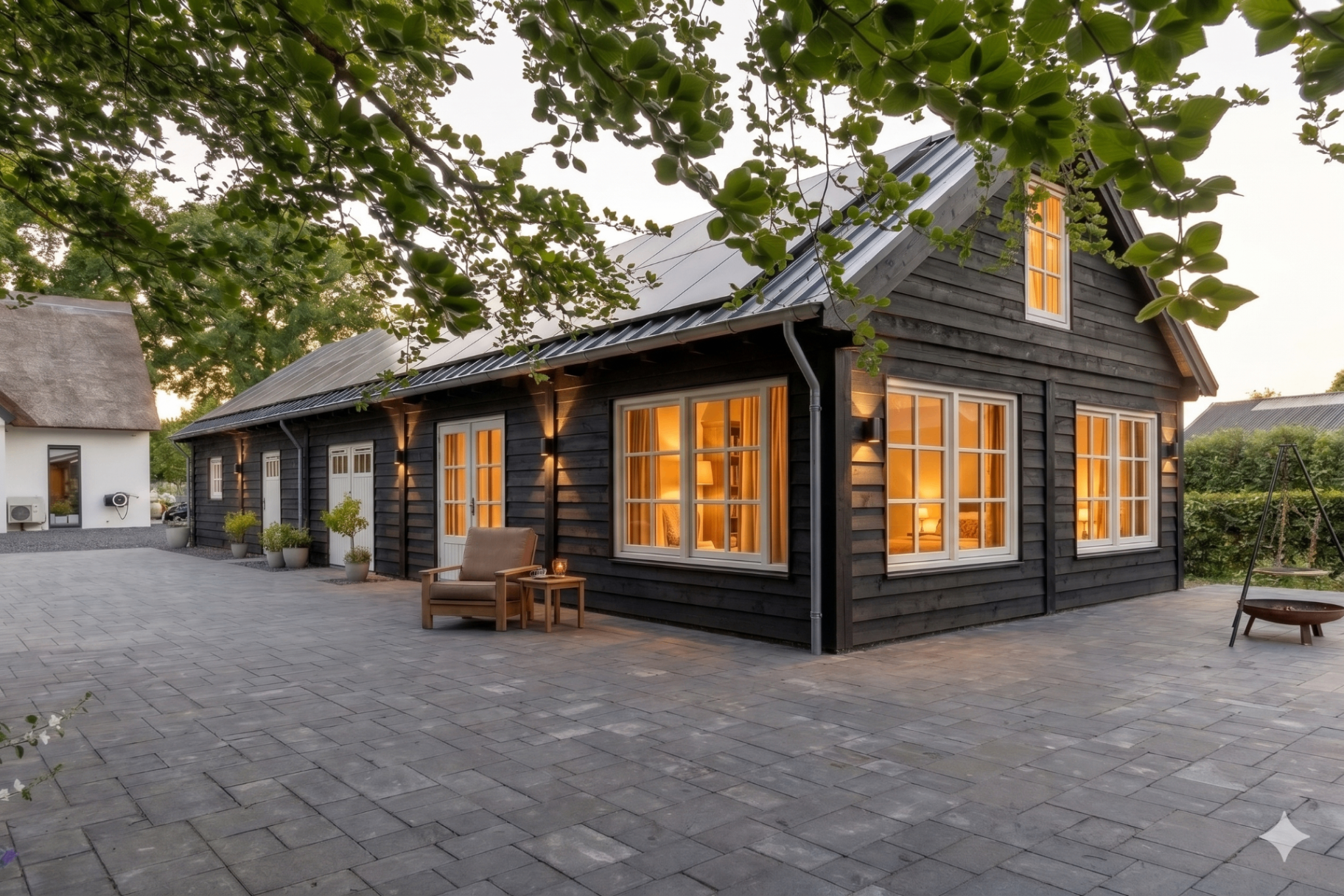 Zwarte houten schuur omgebouwd tot sfeervolle mantelzorgwoning bij schemering